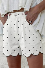 White chino shorts with black polka dots and scalloped hem detail.