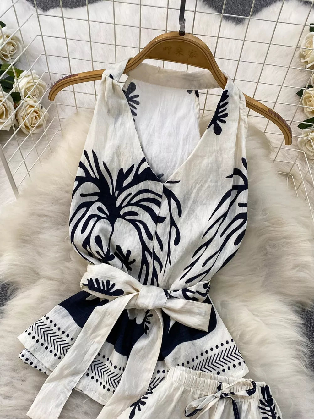 White and navy tropical print halter top with belted waist detail, polyester.