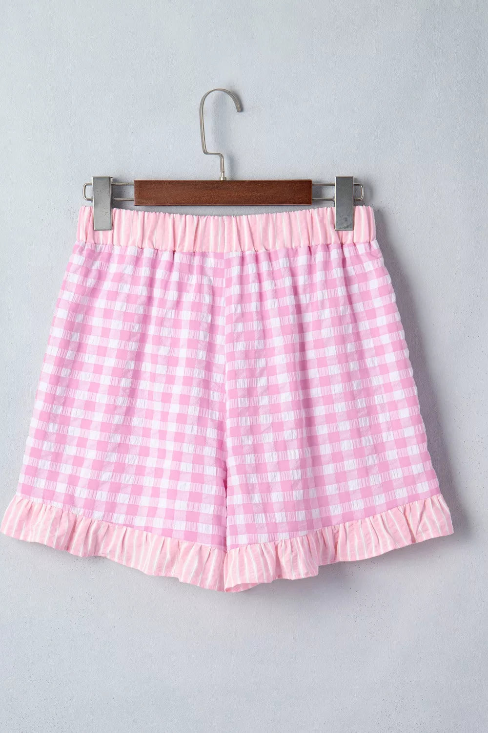 Pink gingham cotton shorts with ruffle hem and drawstring waist.