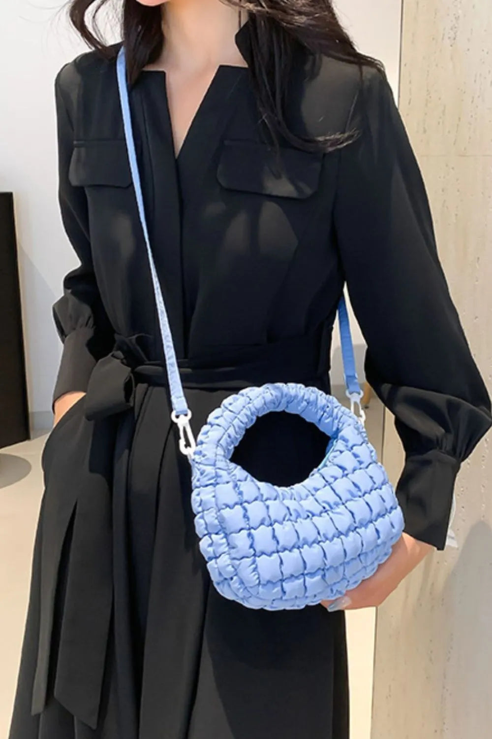 Pastel blue padded crescent crossbody bag with sculptural texture and silver hardware.
