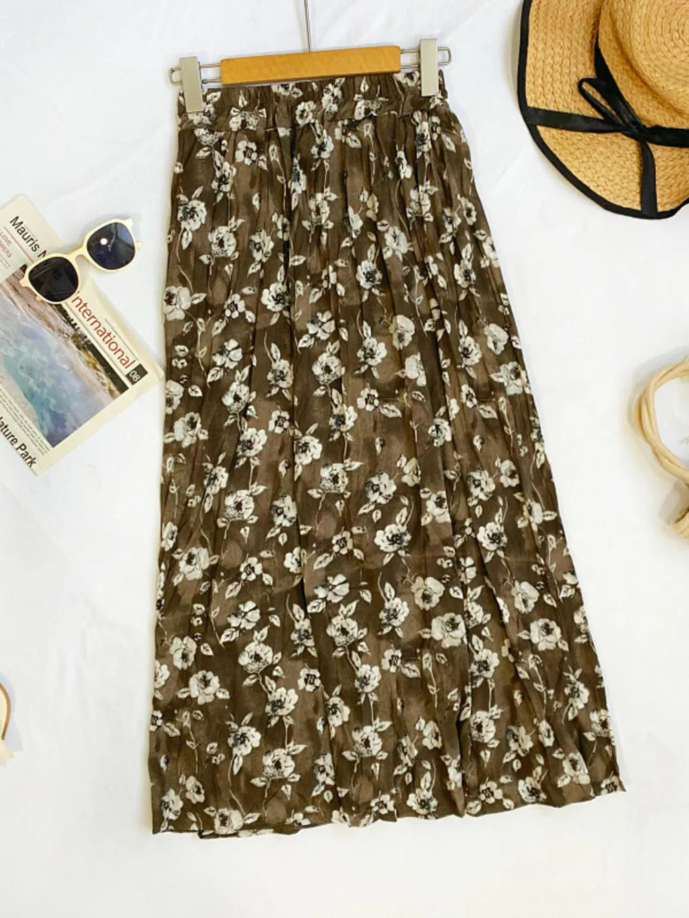 Botanical pleated midi skirt in brown with white floral print, crinkled fabric, and elastic waist.