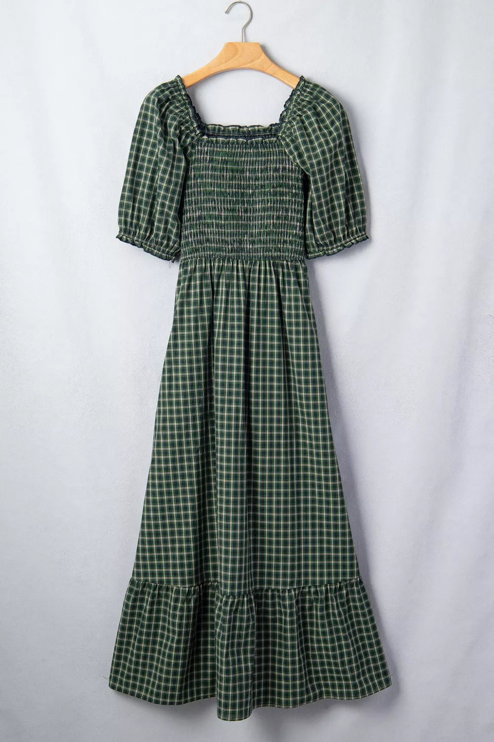 Green plaid maxi dress with smocked bodice, square neck, puff sleeves, and ruffled hem.