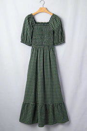 Green plaid maxi dress with smocked bodice, square neck, puff sleeves, and ruffled hem.