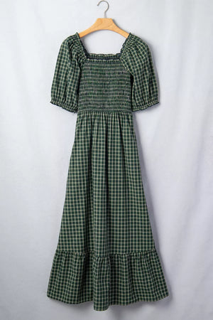 Green plaid maxi dress with smocked bodice, square neck, puff sleeves, and ruffled hem.