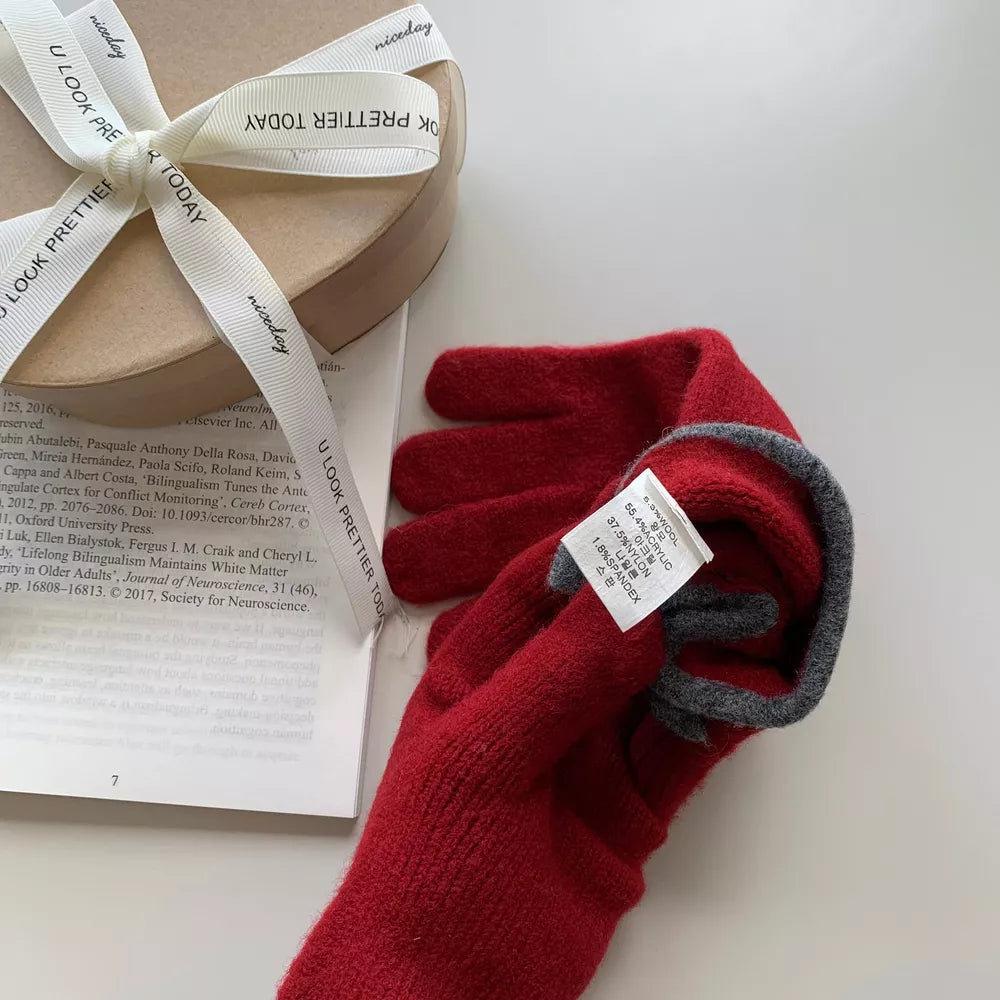 Deep red knit gloves with gray trim and a small bow detail, shown with a gift box.