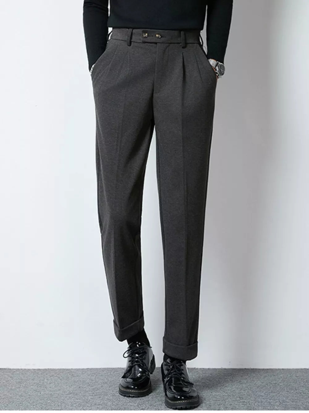 Men's dark gray tailored pleated dress pants with cuffed hems.