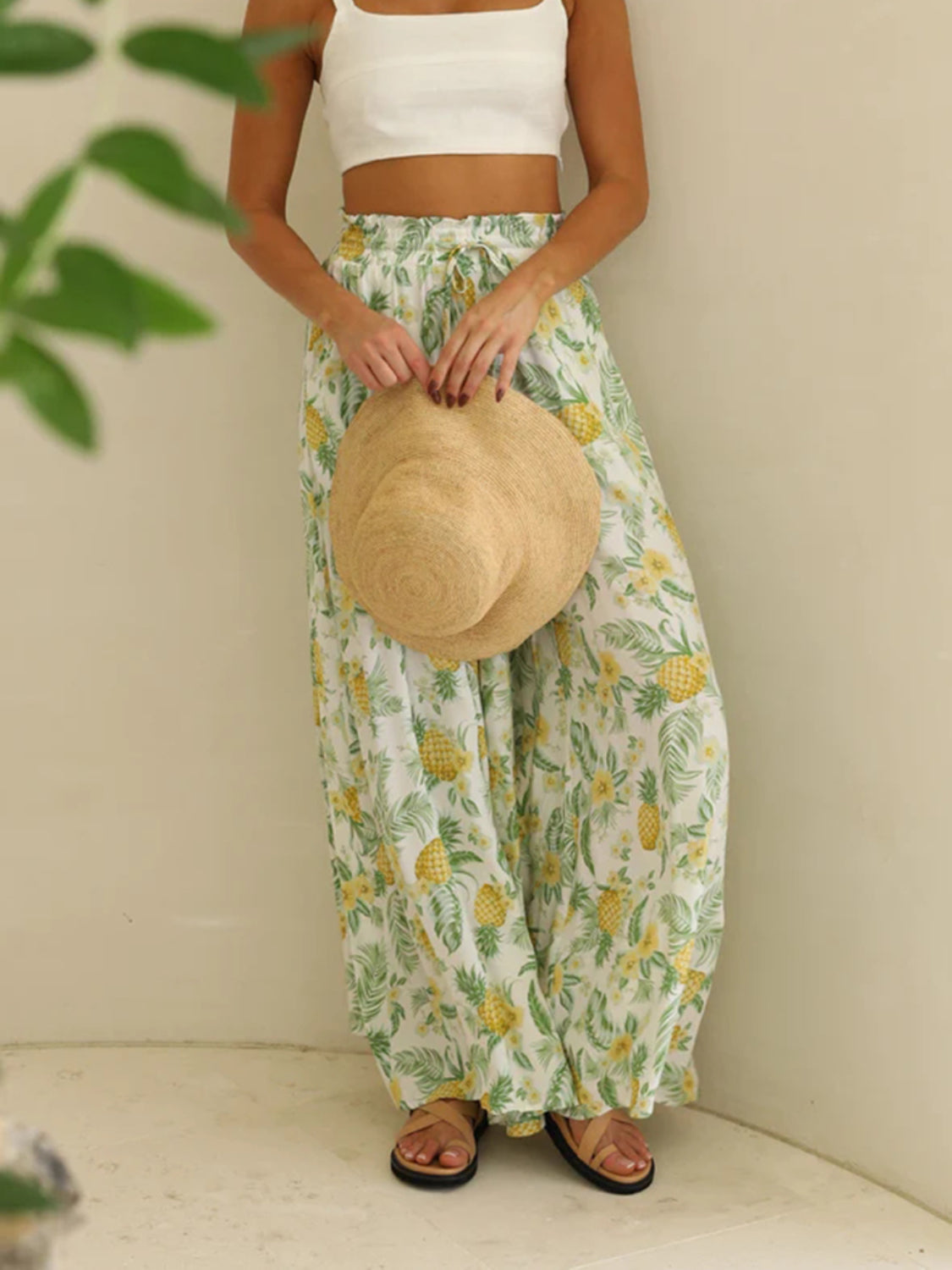 Pineapple print palazzo trousers in white with yellow pineapples and green leaves, featuring a drawstring waist.