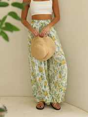 Pineapple print palazzo trousers in white with yellow pineapples and green leaves, featuring a drawstring waist.