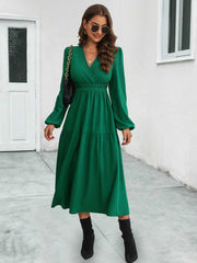 Dark green tiered midi dress with V-neck, long sleeves, and gathered waistline.