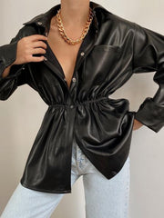 Black faux leather shirt jacket with gathered waist and button front, styled with jeans.