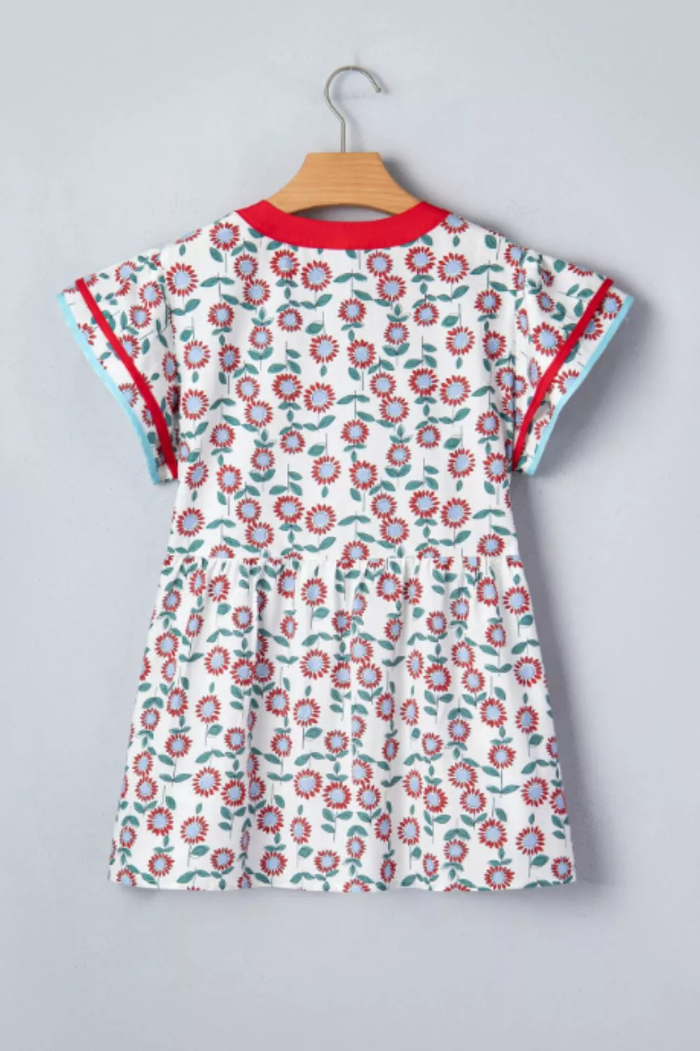 White cotton blouse with vibrant floral print, ruffle sleeves, and contrast trim.