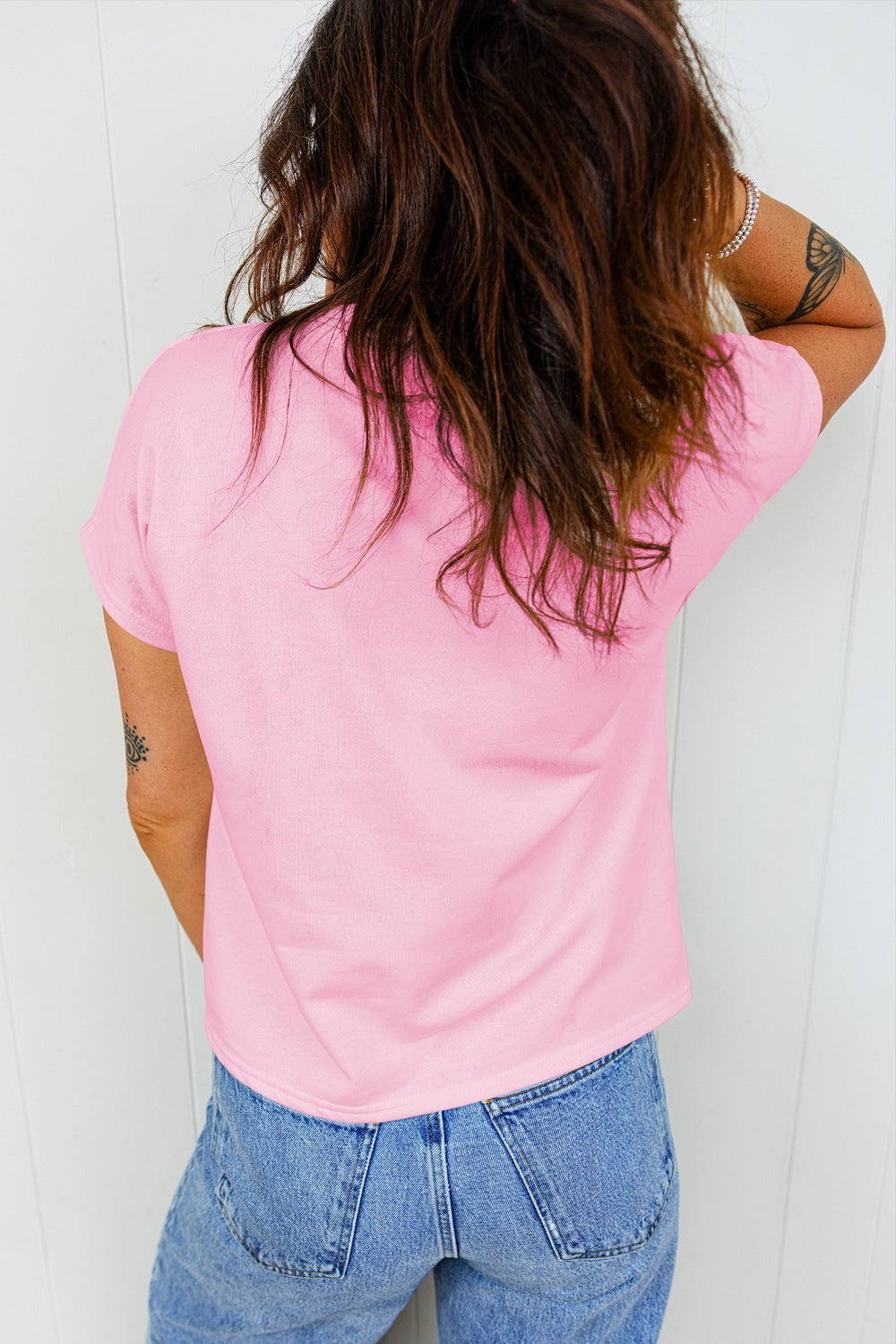Pink cotton t-shirt with crew neck and short sleeves, styled with jeans.