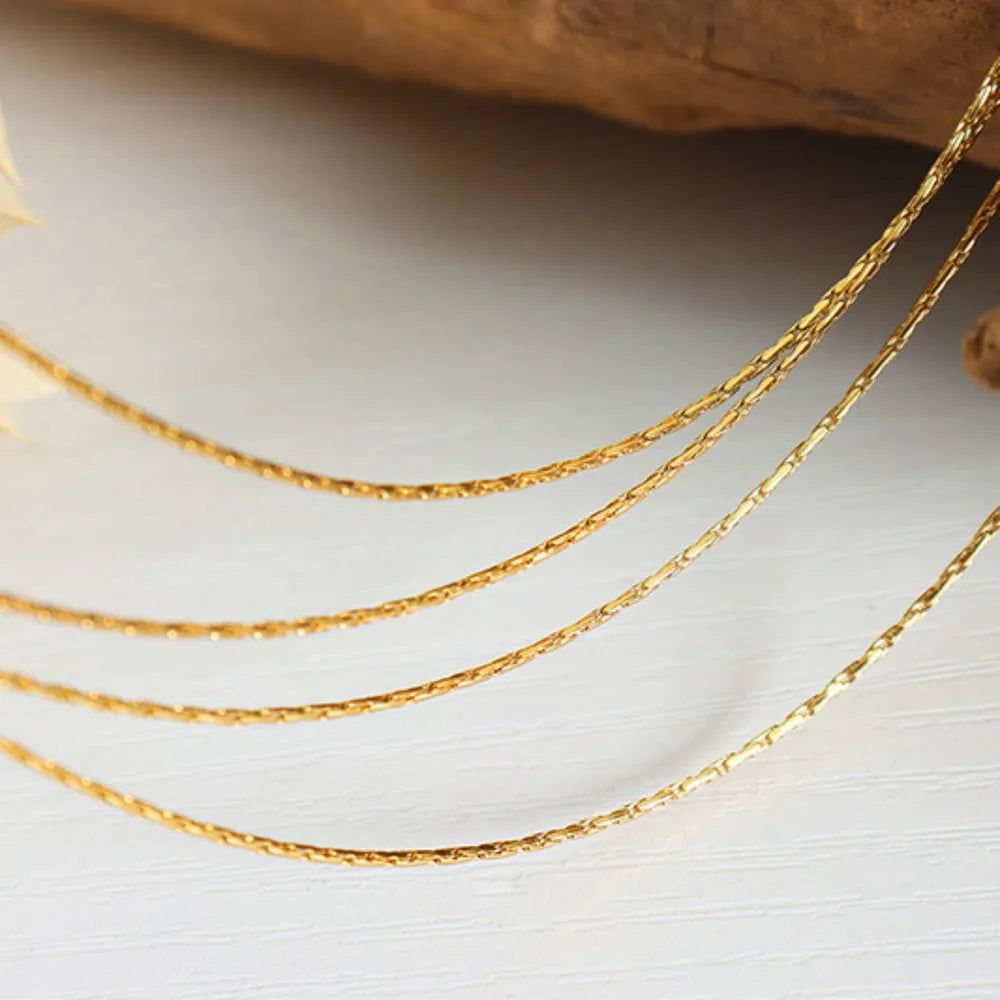 Delicate multi-strand gold-plated collar necklace with textured chains.