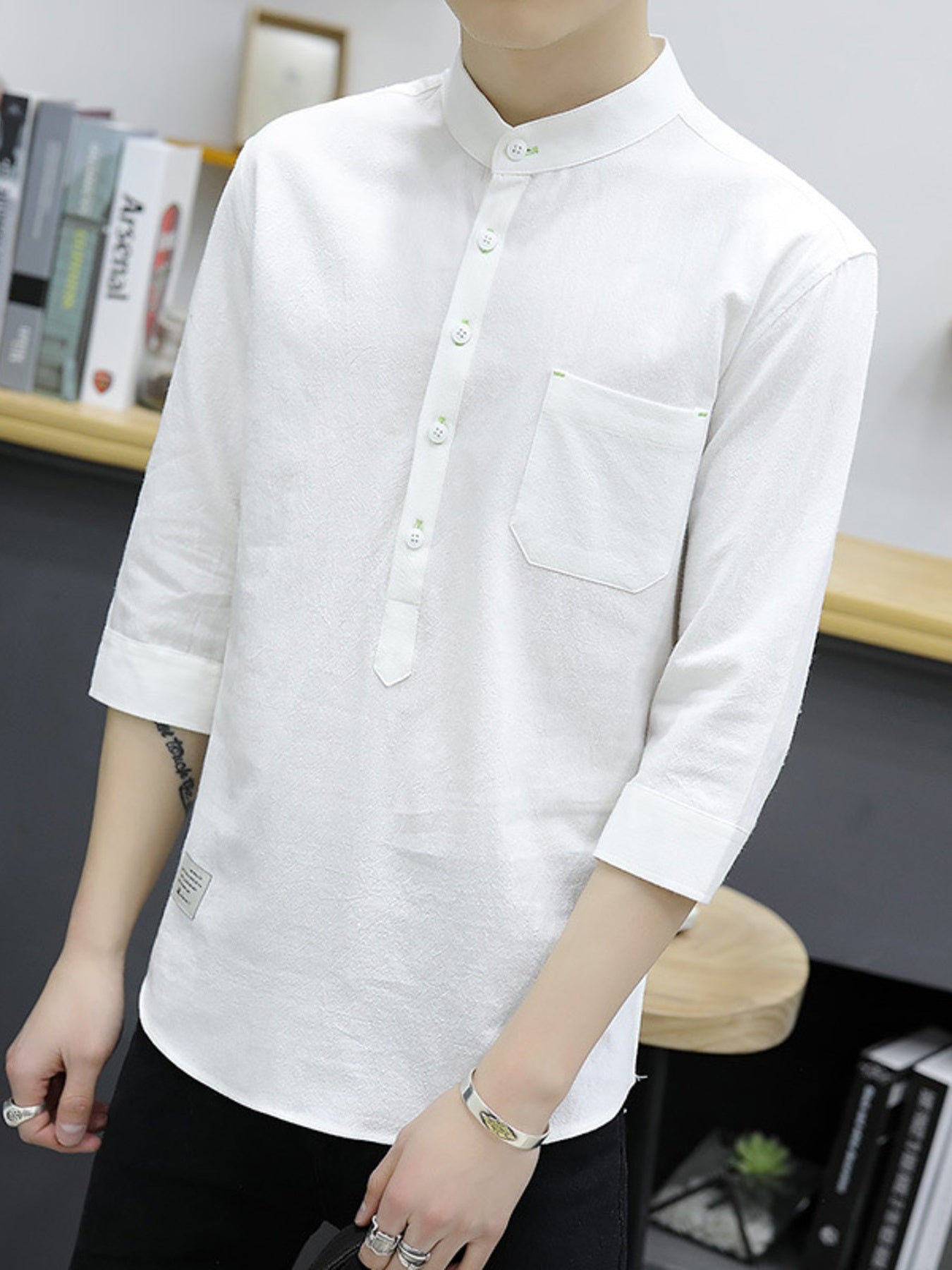 White cotton shirt with button detail, mandarin collar, chest pocket, and 3/4 sleeves.