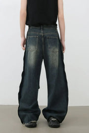 Distressed dark wide leg denim jeans with side slits and raw hems.