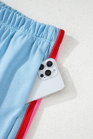 Light blue activewear shorts with rainbow stripe detail and elastic waistband, showing pocket detail.