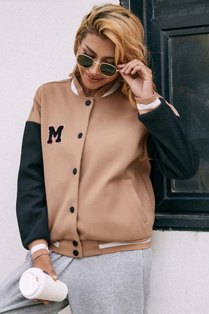 Camel bomber jacket with black sleeves and an M patch, featuring snap buttons and striped trim.