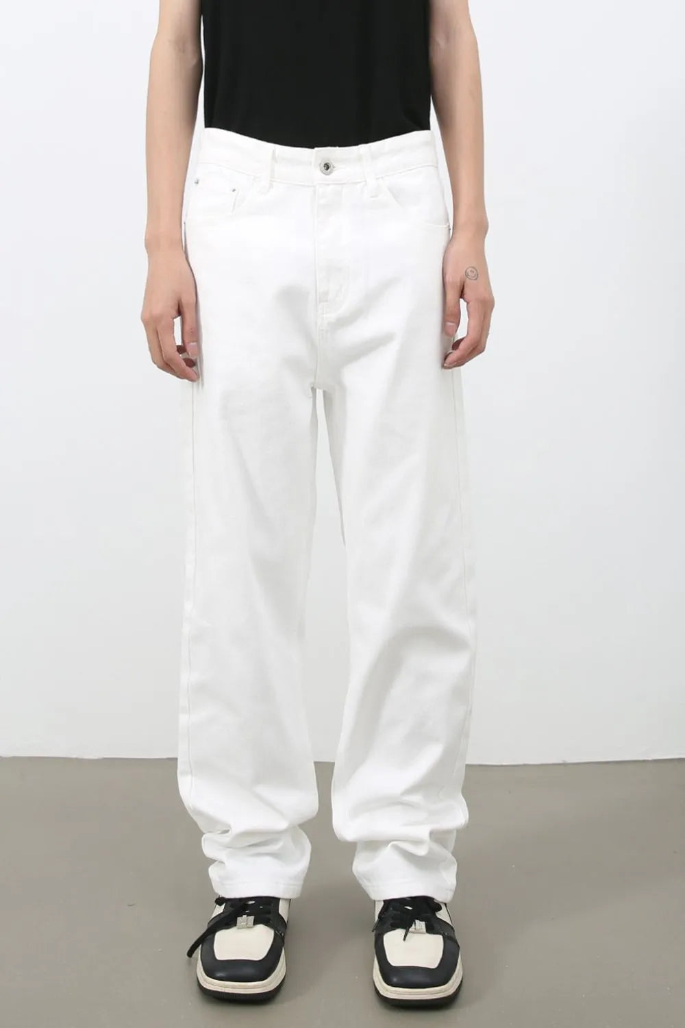 Relaxed white denim jeans with a modernist silhouette, styled casually.