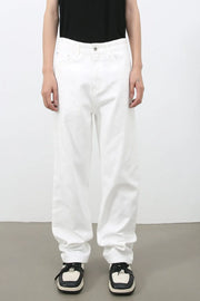Relaxed white denim jeans with a modernist silhouette, styled casually.
