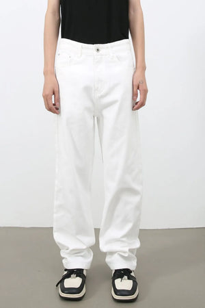 Relaxed white denim jeans with a modernist silhouette, styled casually.