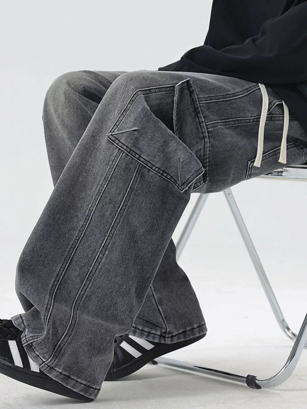 Oversized dark gray denim cargo jeans with drawstring waist and flap pockets.