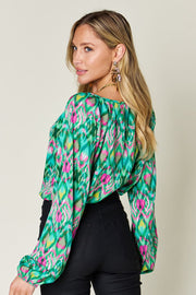 Green ikat print blouse with voluminous sleeves and a gathered neckline.