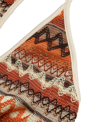 Geometric pattern halter jumpsuit in beige, orange, and brown knit fabric with a zigzag design.