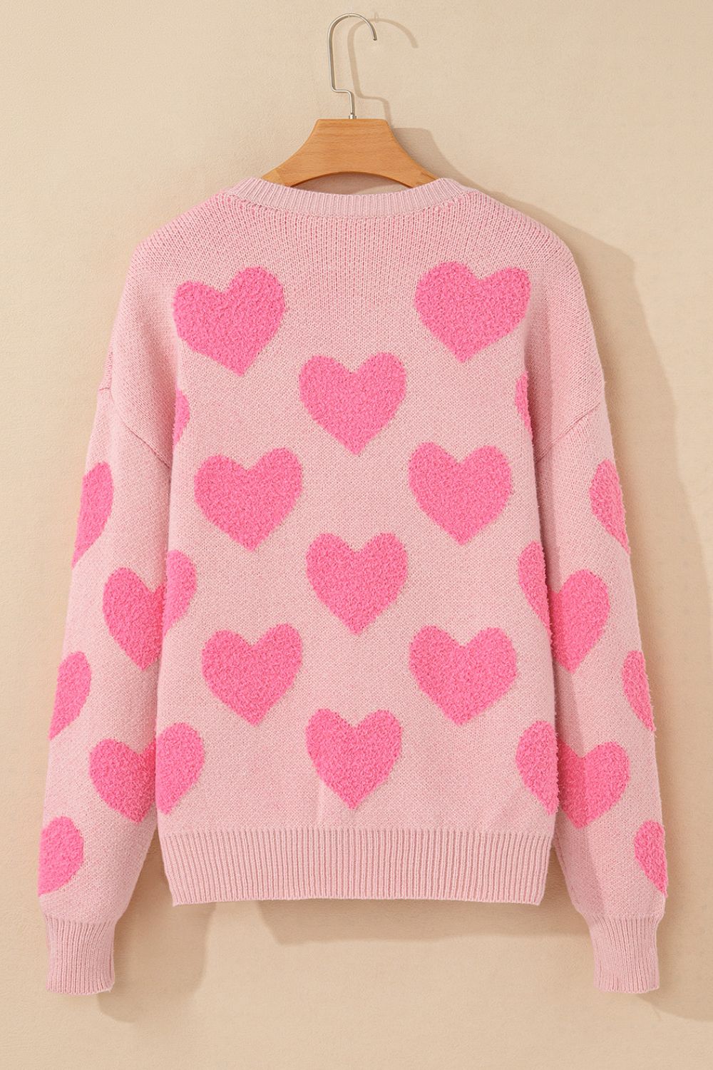 Blush pink knit sweater with allover textured bright pink heart motif.