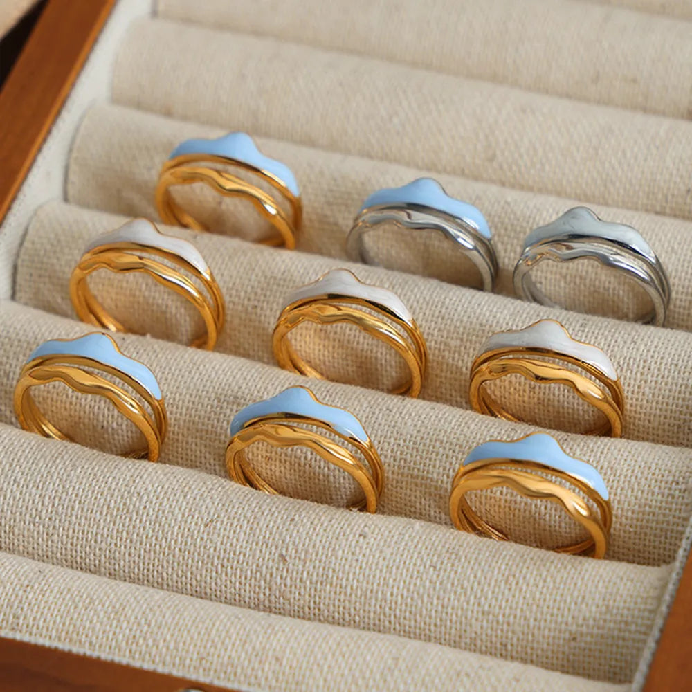 Sculpted enamel wave rings in gold, silver, light blue, and white.