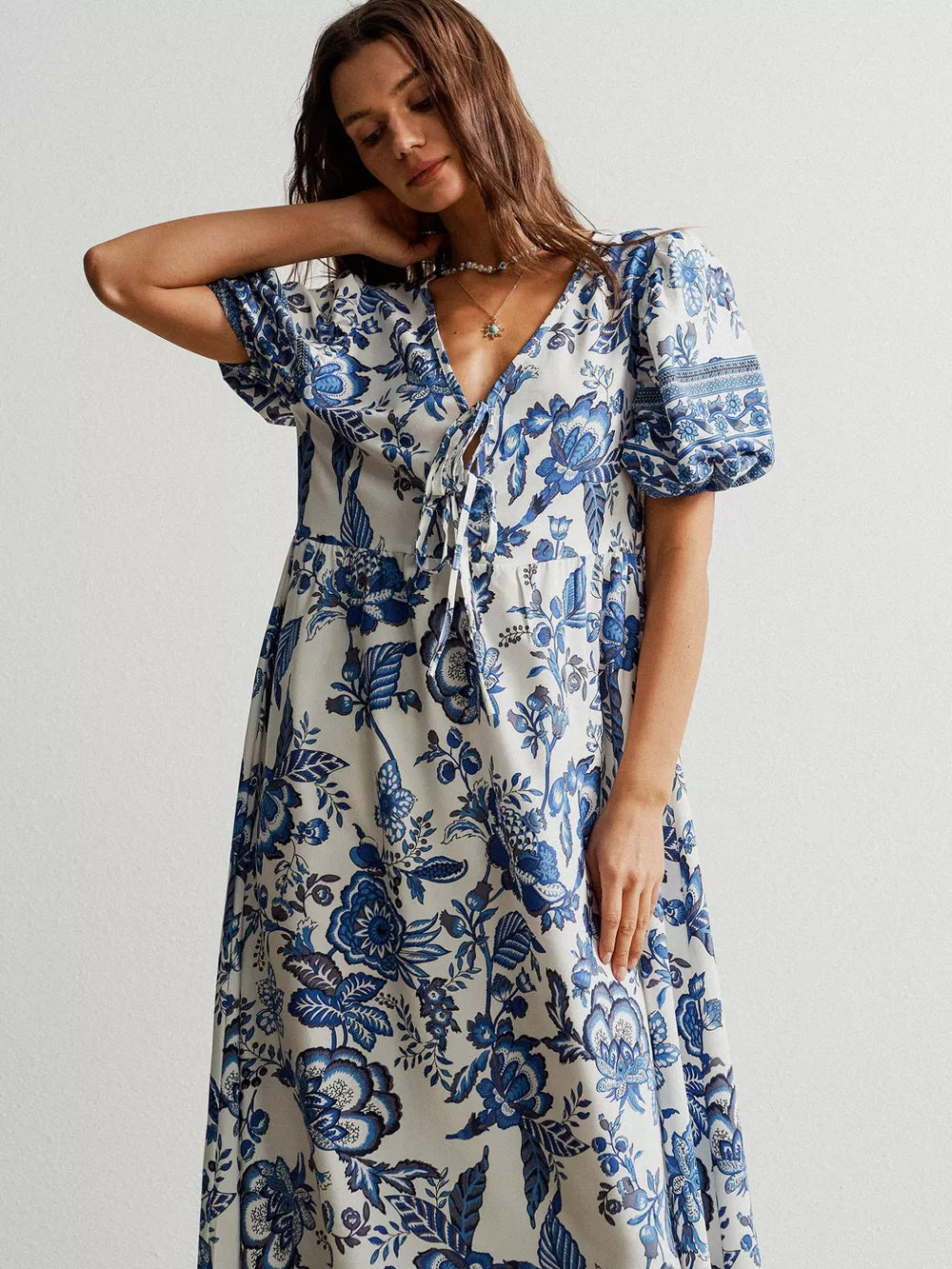 Maxi dress with blue floral print, tie-neck, short puff sleeves, and flowing skirt.