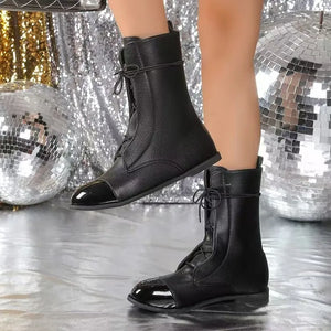 Black leather ankle boots with lace-up front and patent cap toe.