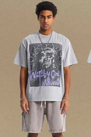 Gray oversized t-shirt with a graphic print of a face and text that reads "Worthy One Advent".