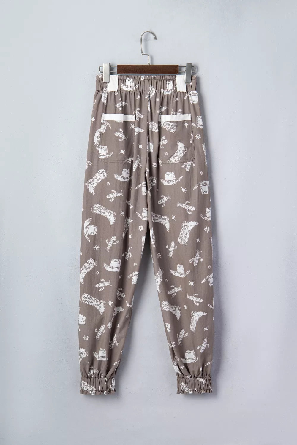 Vintage western print drawstring joggers in taupe cotton with cowboy boots and cactus pattern.