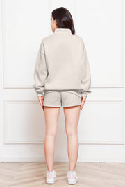 Ivory quarter-zip loungewear set with mock neck sweatshirt and shorts.
