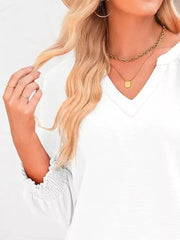 White long sleeve blouse with smocked cuffs and V-neck