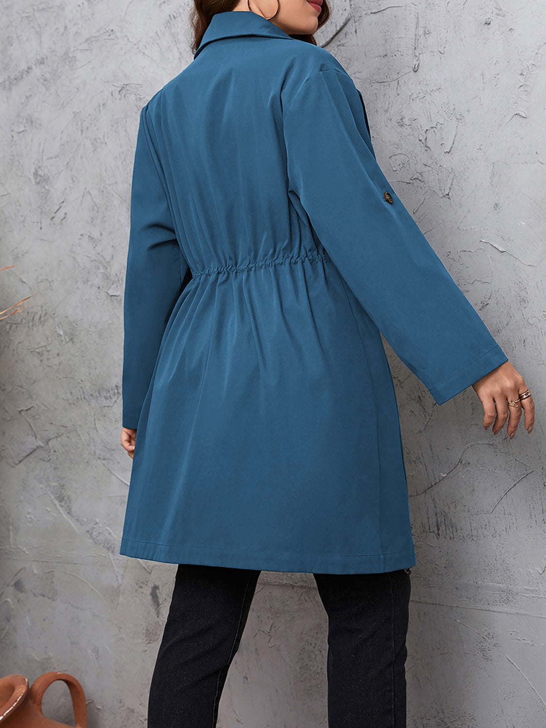 Dusty blue trench coat with gathered waistline and roll-up sleeves.