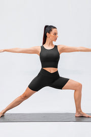 Black cross-waist active bike shorts with a high-rise fit and mid-thigh length.