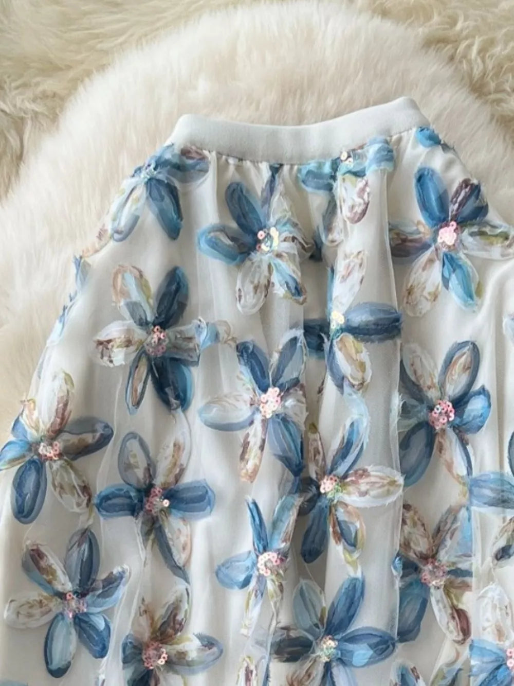 Layered floral skirt with blue flowers and sequins on sheer fabric.