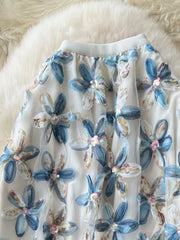Layered floral skirt with blue flowers and sequins on sheer fabric.