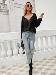 Black lace-inset blouse with V-neck and long slit sleeves.