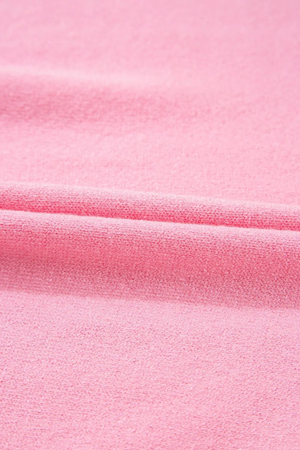 Pink knit blouse with textured fabric and a folded detail.