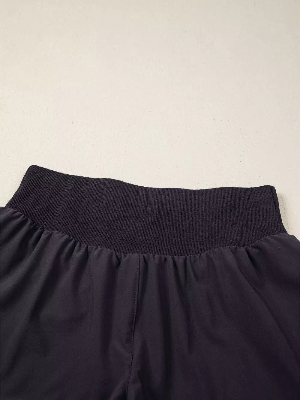 Dark navy athletic jogger shorts with a ribbed high waistband and gathered fabric.