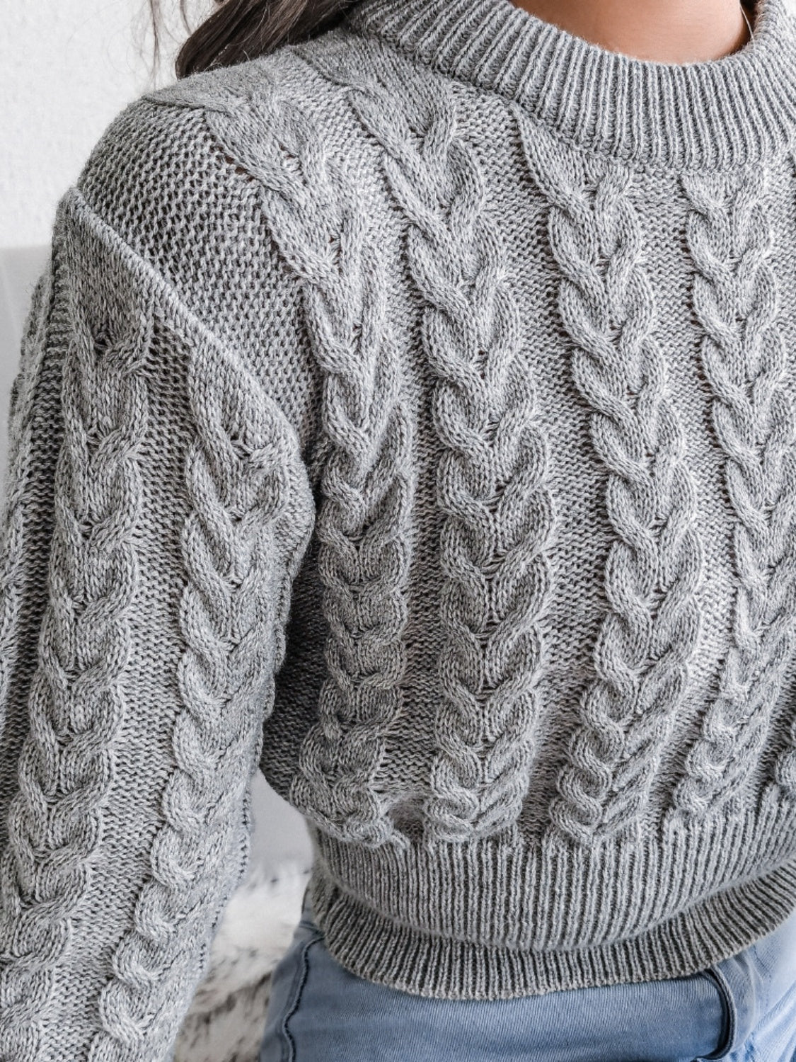 Dark gray acrylic cable knit cropped mock neck sweater with ribbed cuffs and hem.