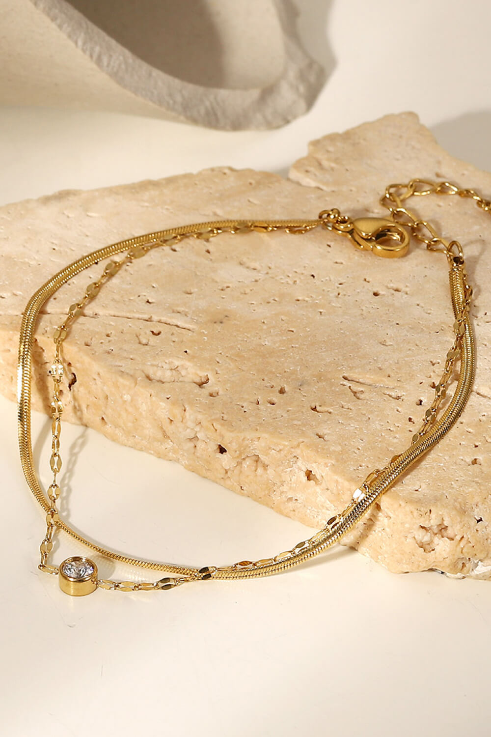 Gold double-strand pavé charm bracelet with a single clear stone detail.