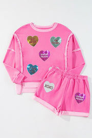 Pink loungewear set with sequin heart appliques and text details.