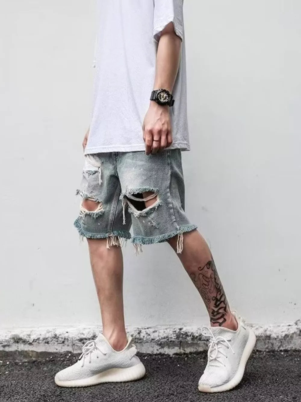 Men's distressed denim shorts in blue with ripped details and frayed hem.