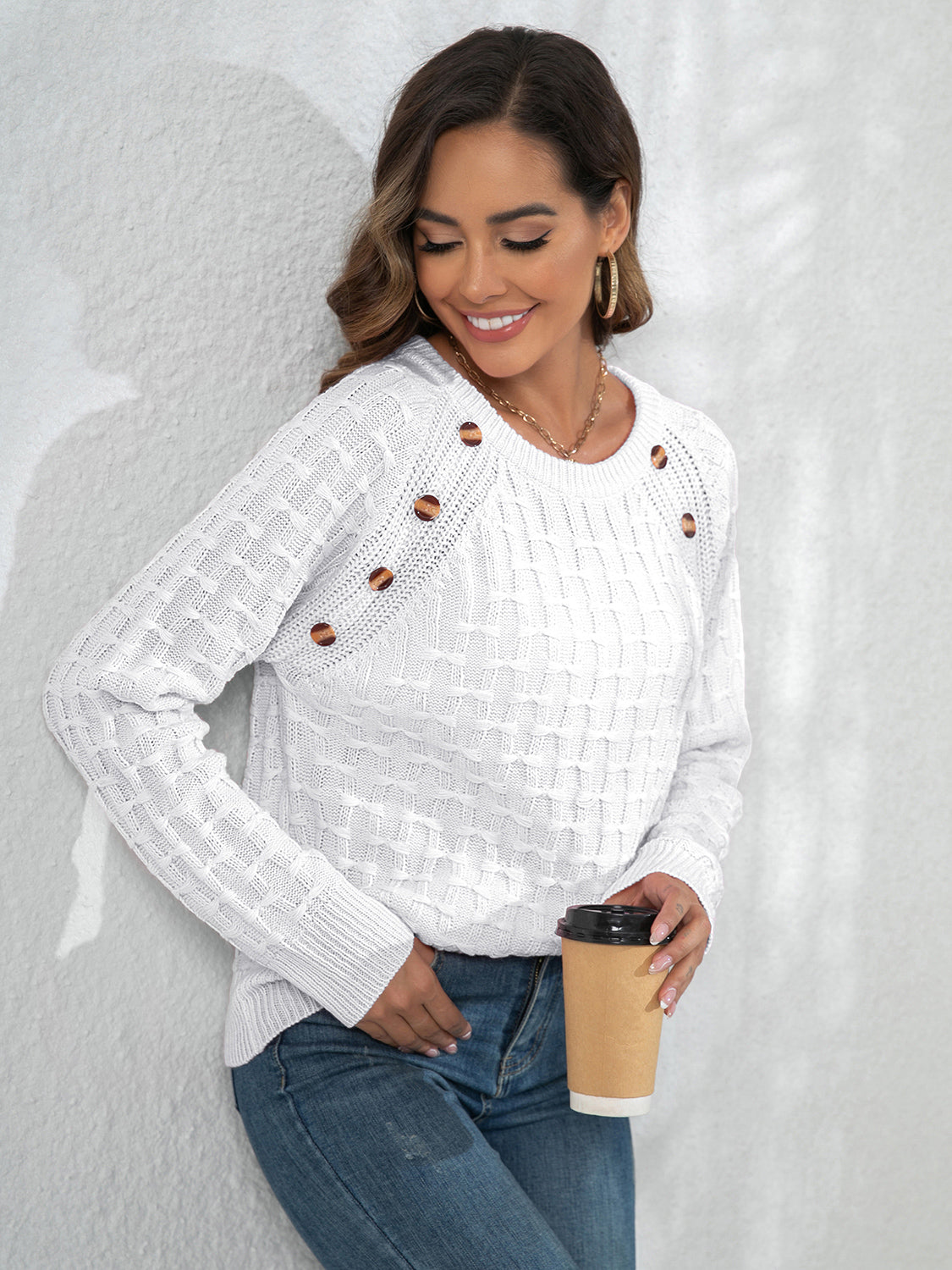 White crewneck knit sweater with textured pattern and button details on the shoulder.