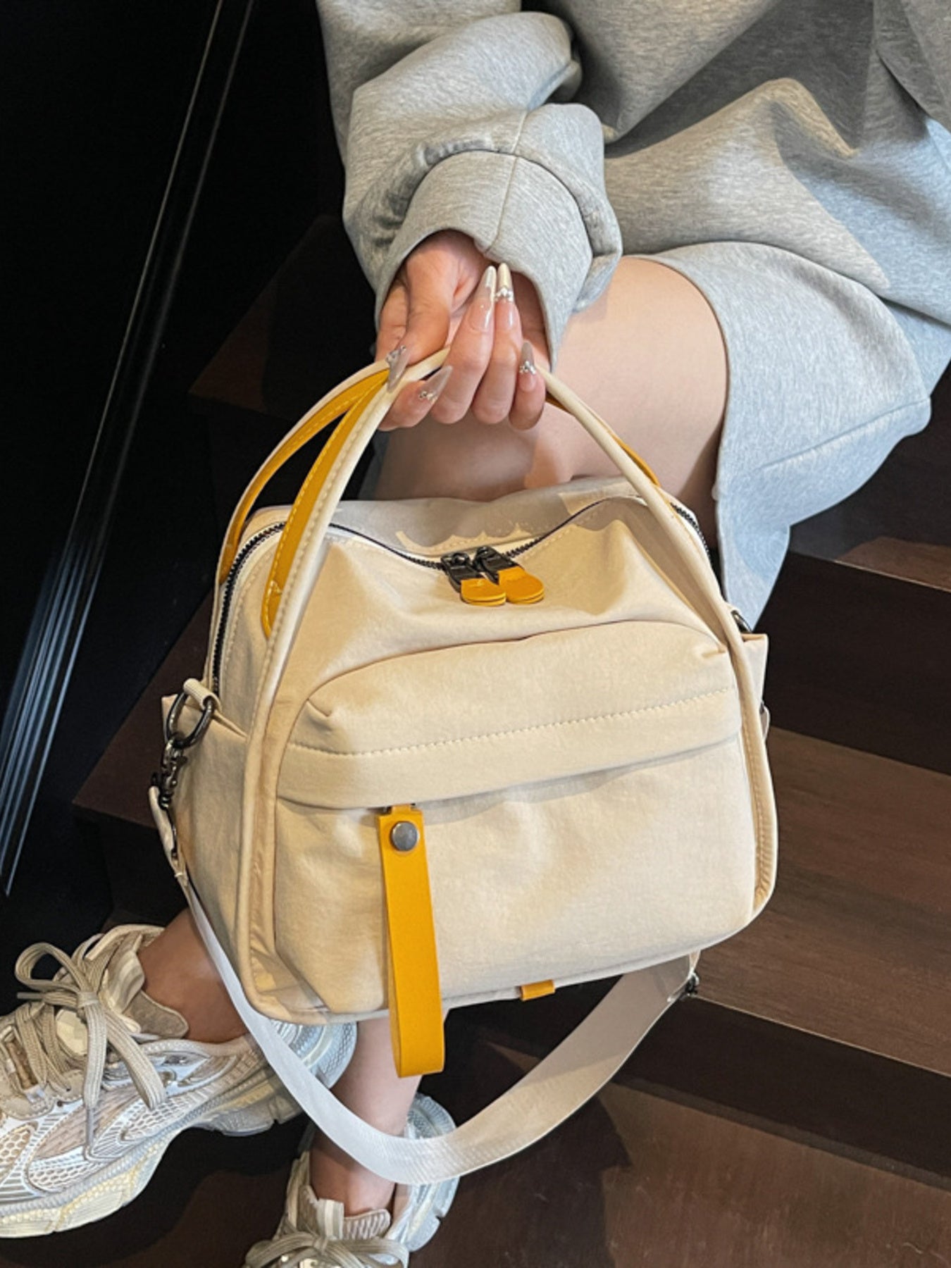 Khaki crossbody bag with yellow pull tab and zipper details, casual style.
