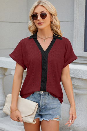 Burgundy perforated panel polo top with black trim and short sleeves.