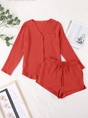 Textured cotton pajama set in orange-red with button-up top and drawstring shorts.